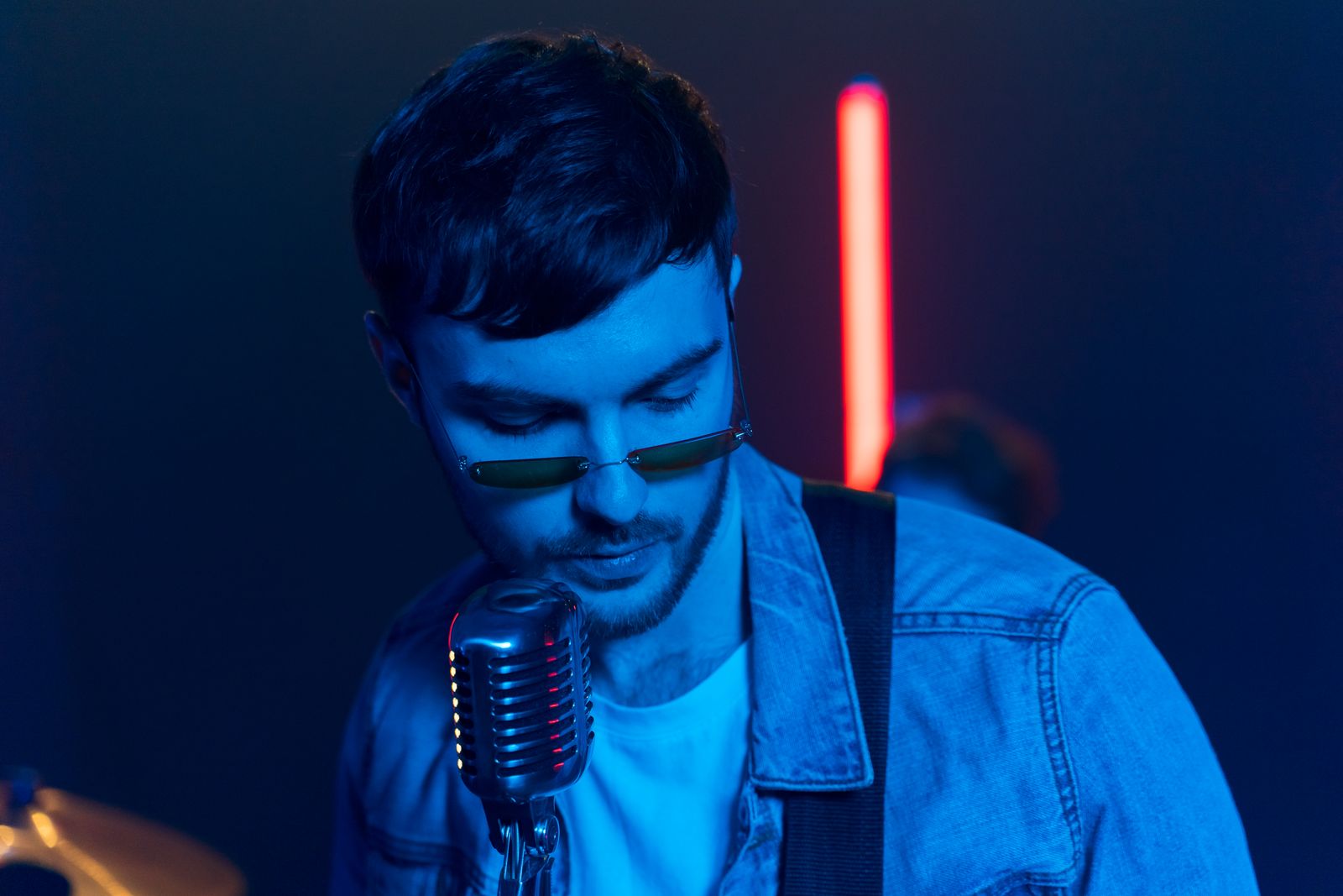 A singer in sunglasses performing into a classic vintage microphone.